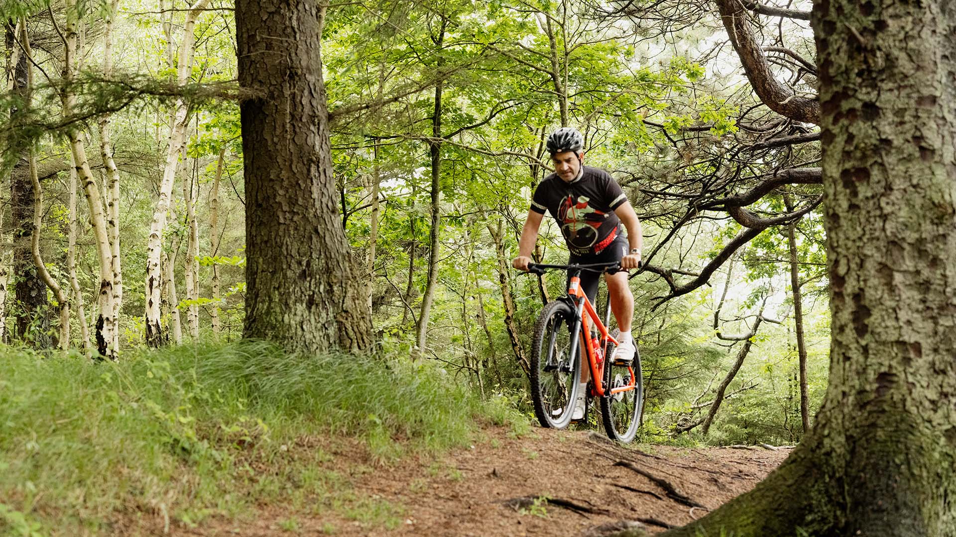 Mand cykler på bmx cykel i skoven, hvor ulykkesforsikringen dækker ved cykelstyrt.